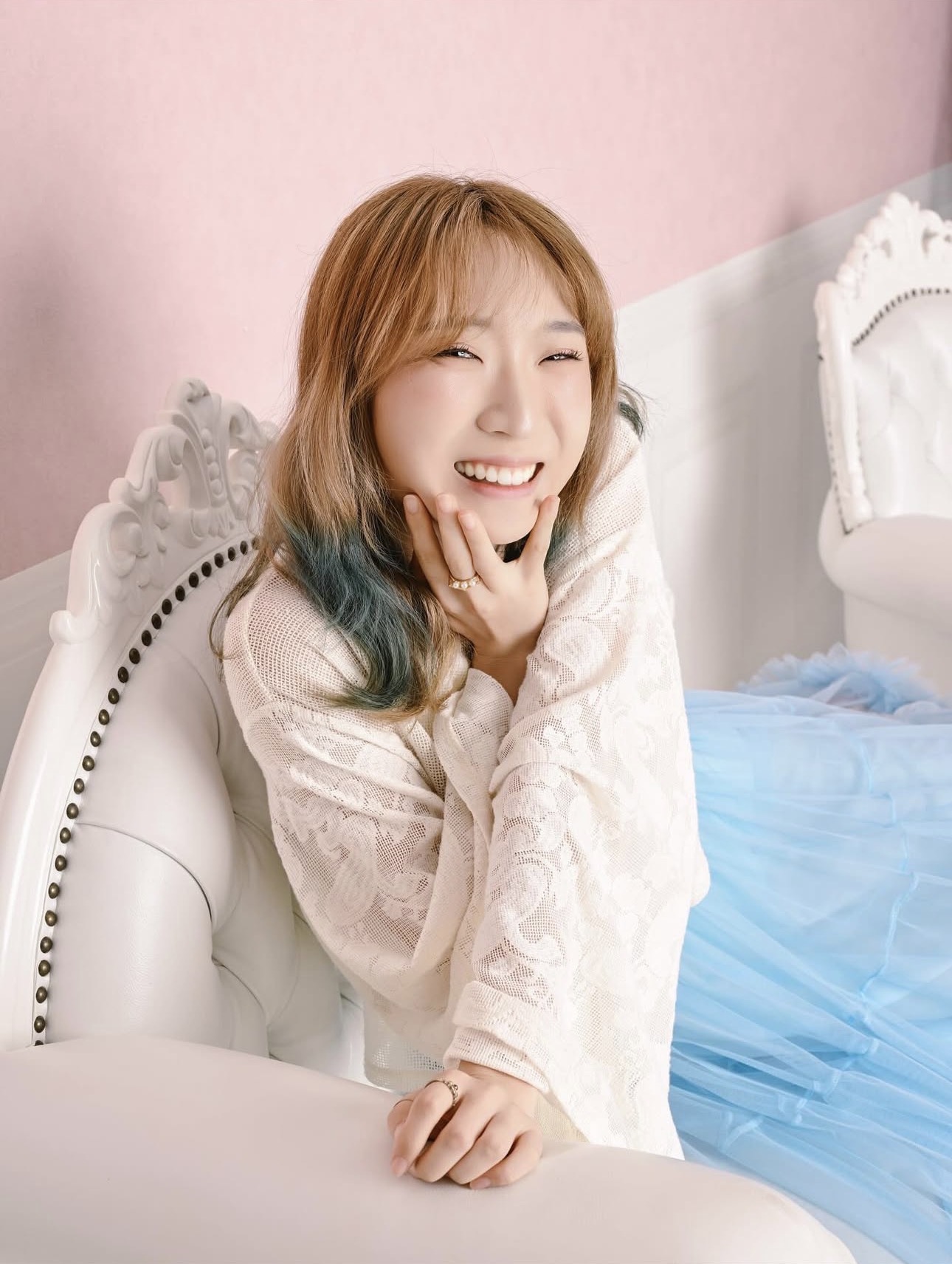 白い椅子と水色の衣装で撮影した笑顔のプロフィール写真