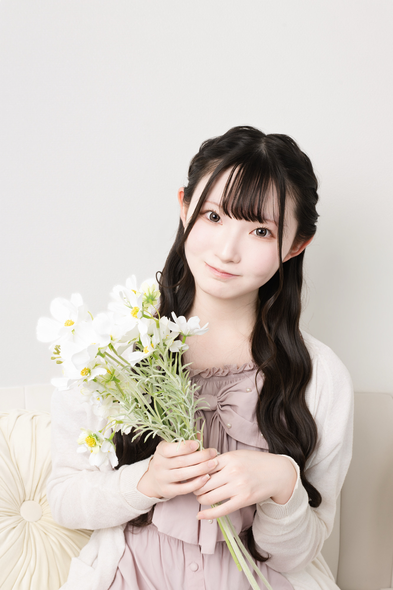 ピンクの私服で白い花を持ったやわらかなプロフィール写真