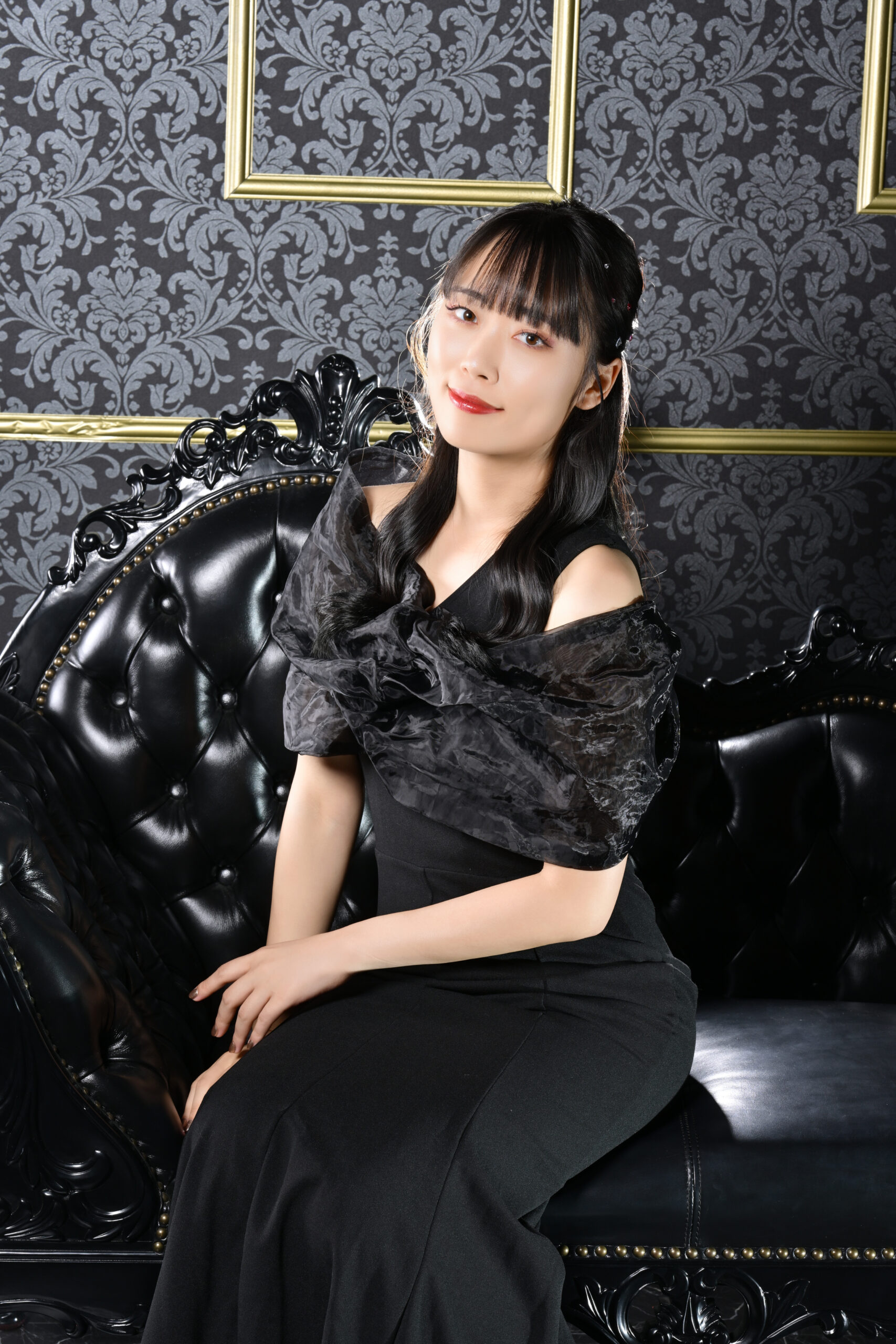 黒いソファに座った黒ドレスの宣材写真