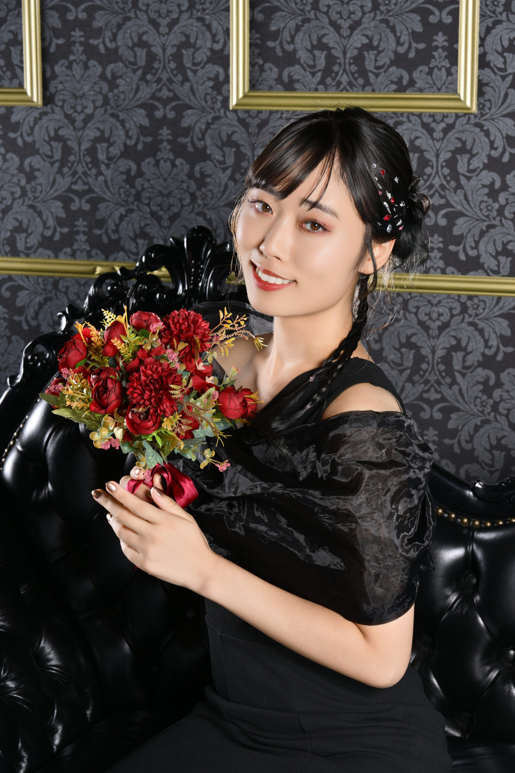赤い花束を持って微笑む黒ドレスの宣材写真