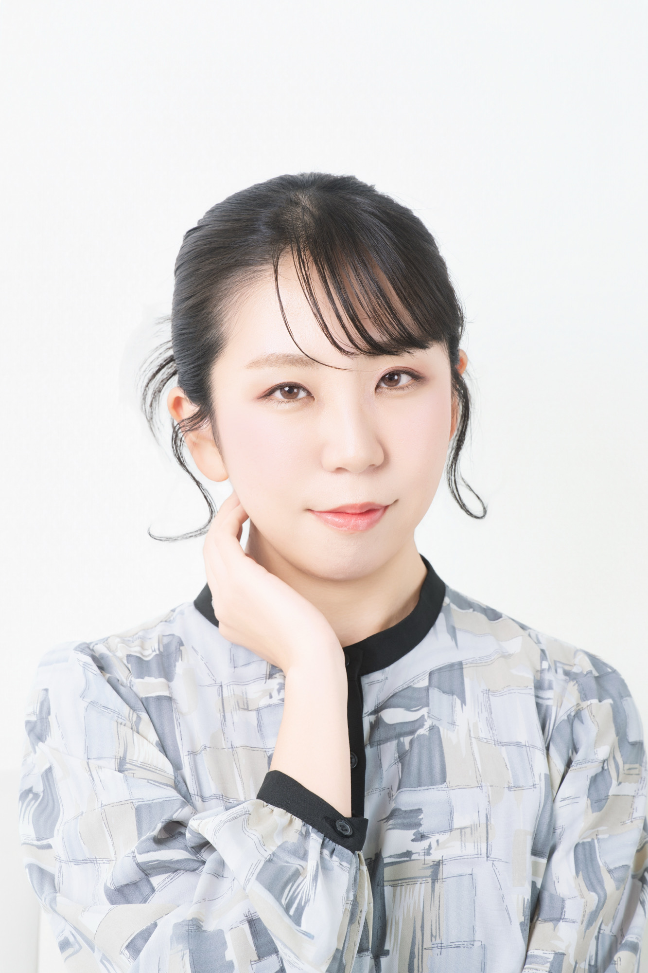 白背景で手を頬に添えたバストアッププロフィール写真